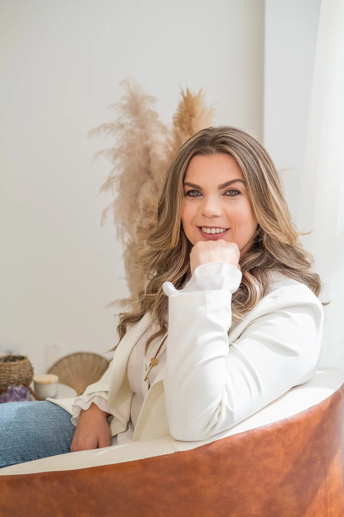 Lucinda sentada em poltrona de couro, sorrindo, em ambiente claro